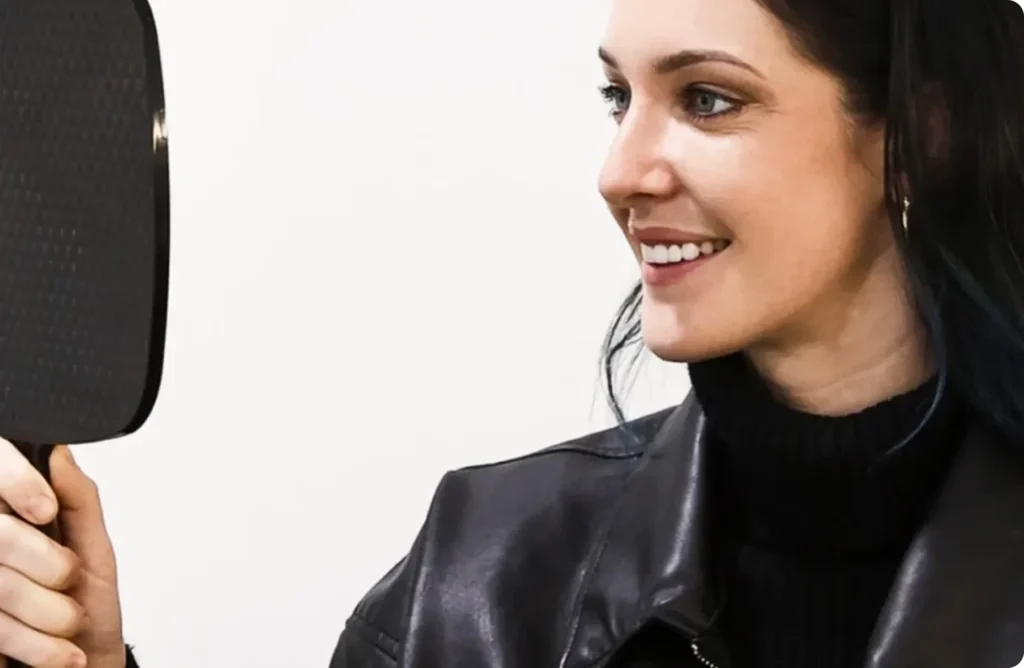 Patient admiring her smile in a mirror after cosmetic dentistry